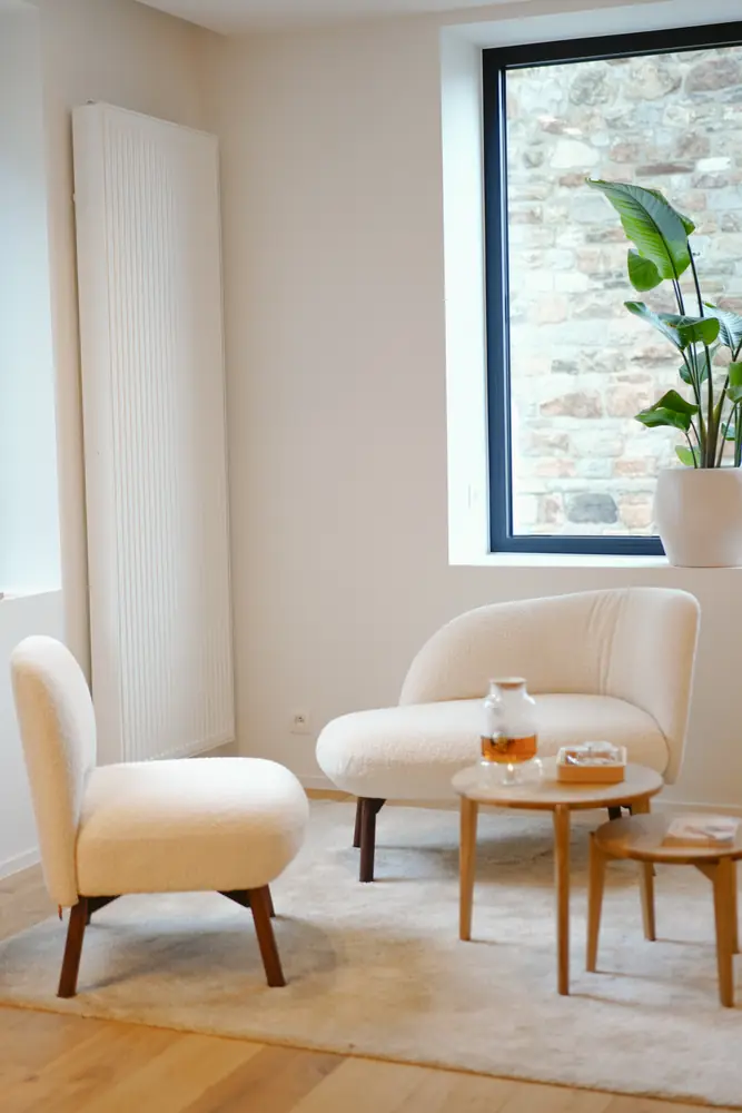Le salon d'accueil de La Maison Cocoon : fauteuils bouclette, table en bois et thé